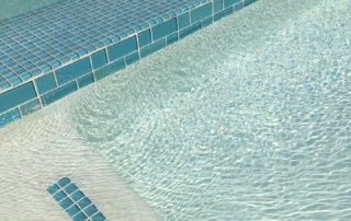 Finish Sparkle Quartz White pool step and spa edge with teal glass tile trim